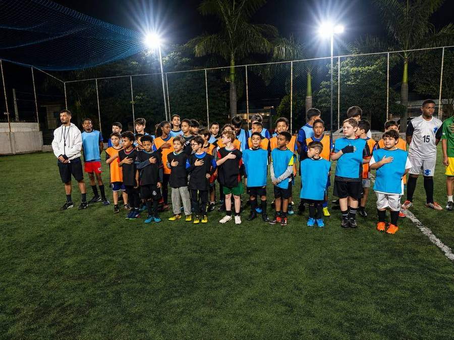 Atletas da Escolinha de Futebol Espaço Saúde durante o hino, antes da partida.